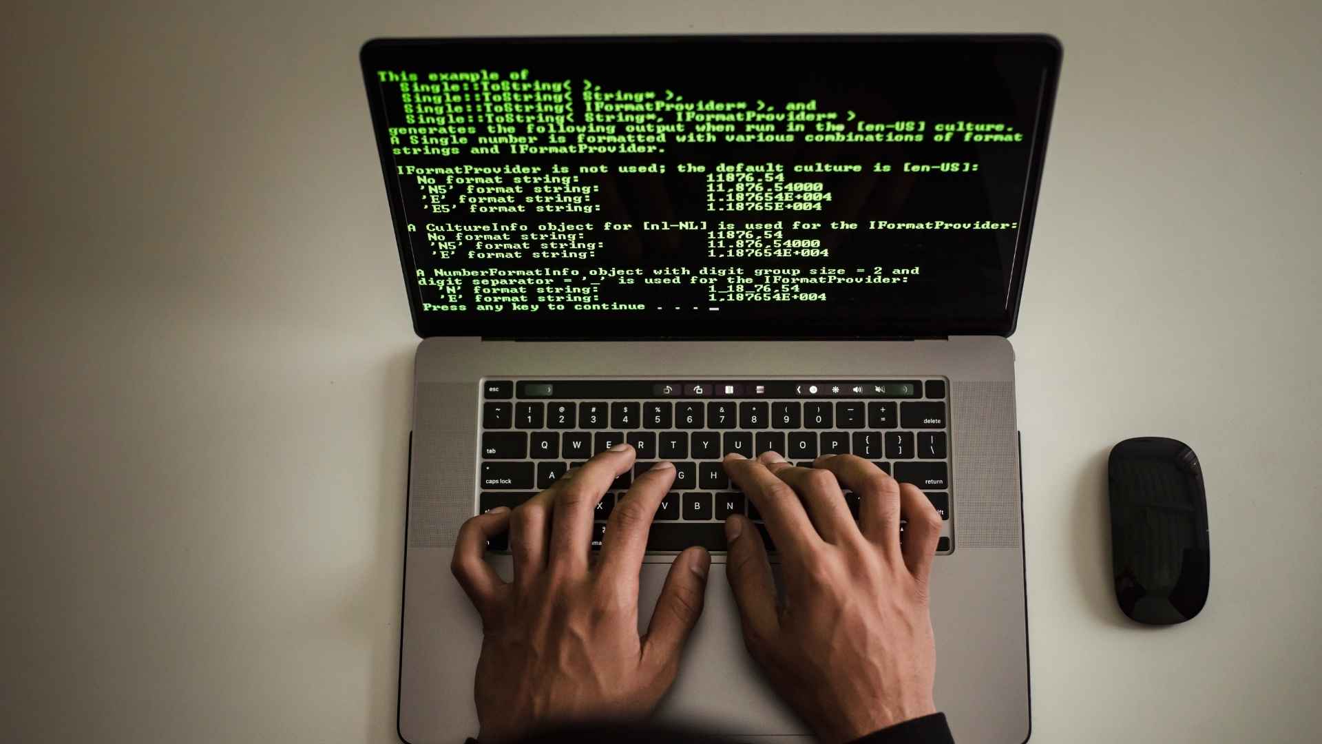 pessoa digitando em um notebook com tela exibindo código de programação em fundo preto.