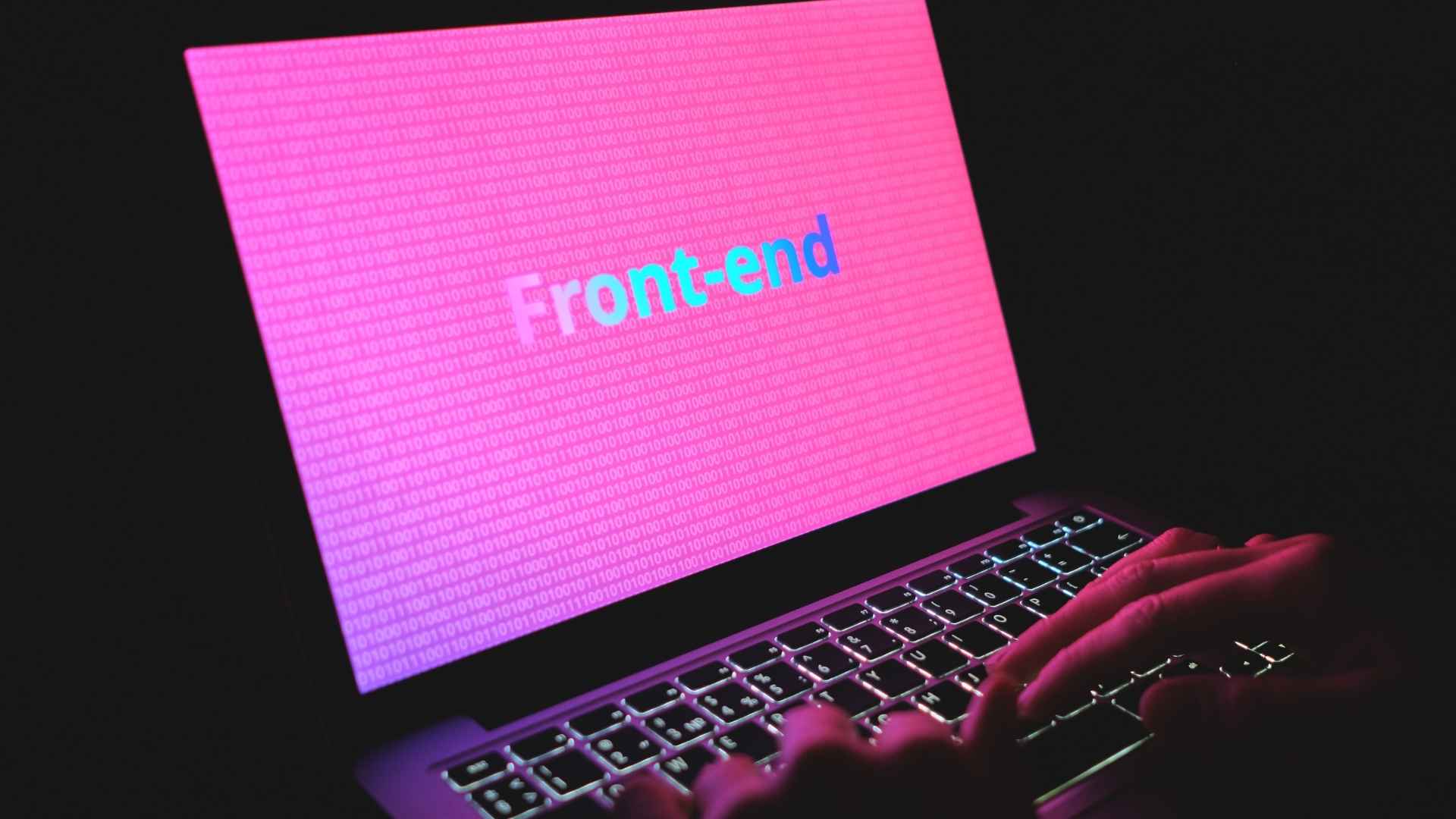 Tela de notebook iluminada em rosa com a palavra “Front-end” ao centro e código binário ao fundo.