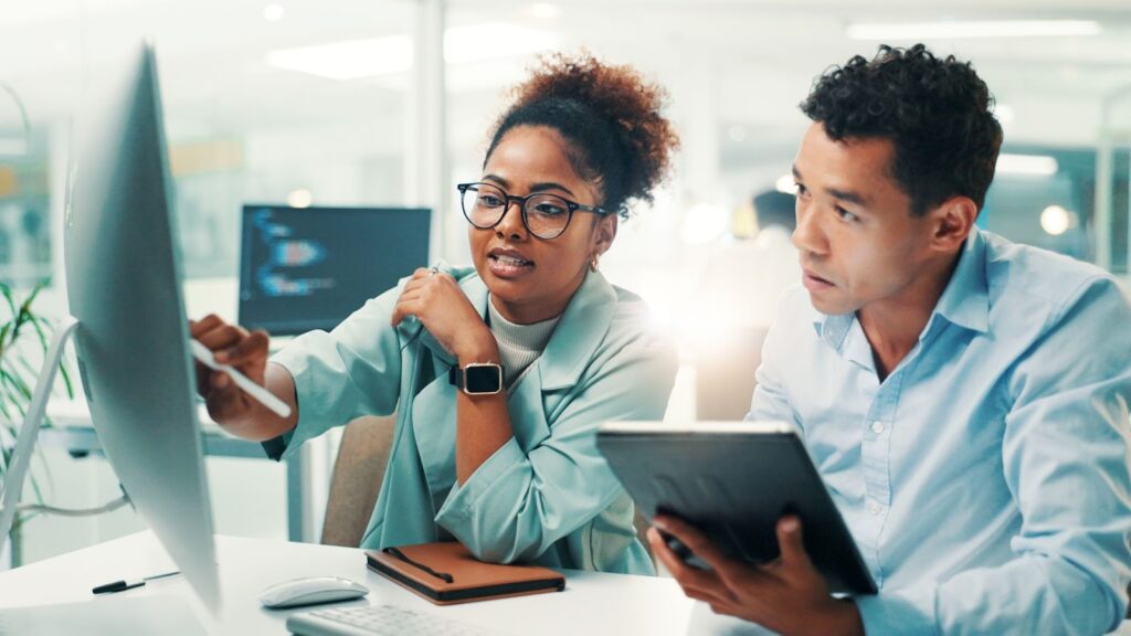 Profissionais de TI discutindo código e soluções de backend em ambiente de trabalho moderno
