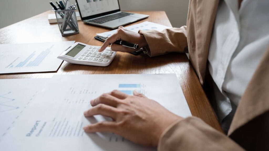 Gestor calculando o turnover da empresa com planilhas e gráficos de desempenho sobre a mesa